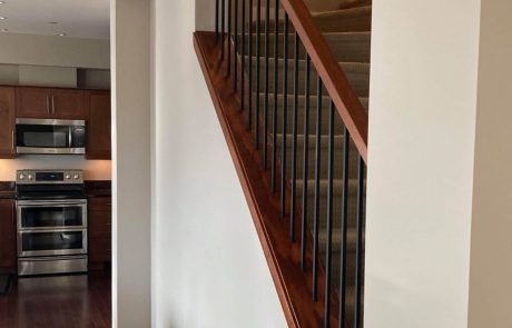 wooden railing staircase with carpet and modern kitchen appliance in esquimalt home