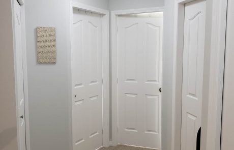 carpeted hallway with light grey walls leading to bedrooms