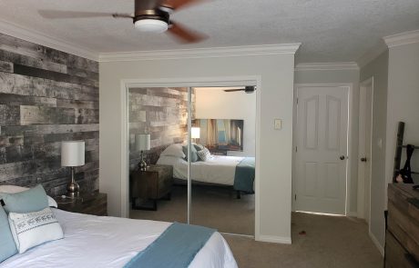 bedroom with mirror sliding door closet and a grey paneled accent wall in esquimalt victoria