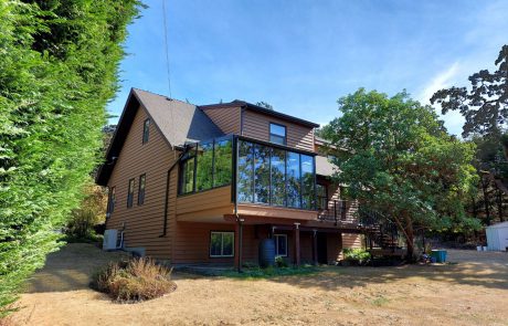 Back of a brown house with solarium and deck