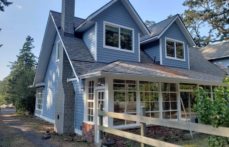 Exterior of a blue house with white frames and a solarium in Metchosin