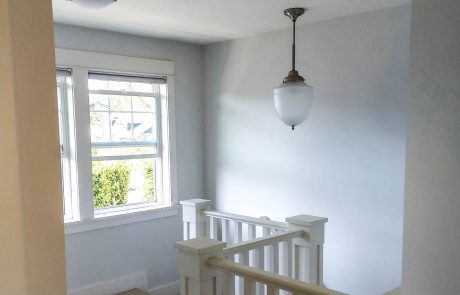 upstairs hallway and staircase with light grey walls and hanging light