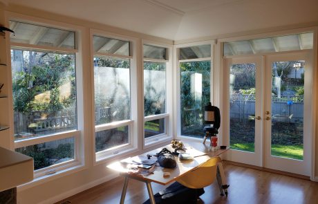 large windows of a dining room facing with a view of the backyard and garden