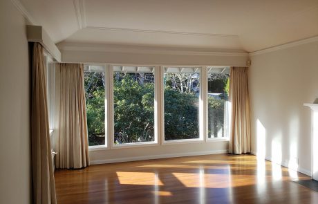 bright open living room with large windows and beige curtains