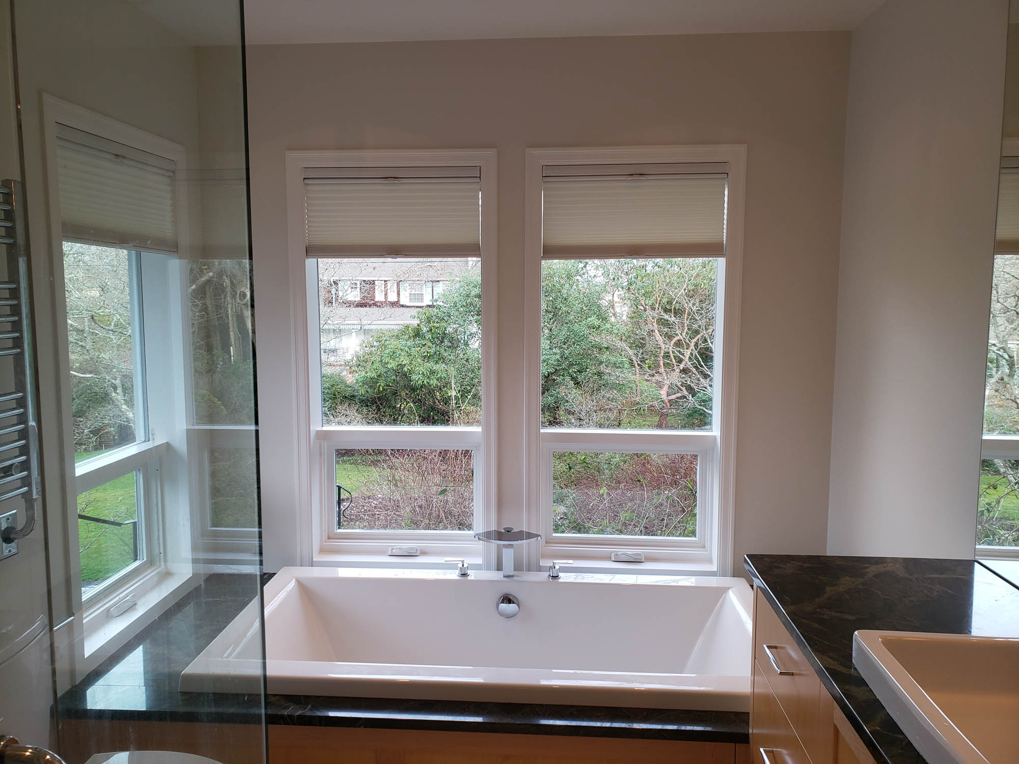 contemporary bathroom with large soaker tub and windows facing a garden in an uplands house in victoria