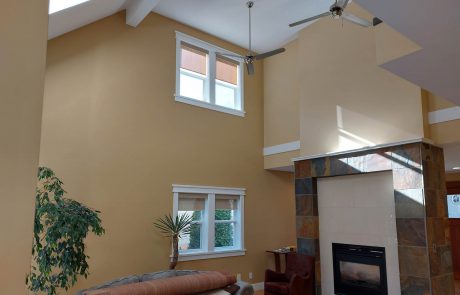 fireplace and high ceiling living room with two ceiling fans and white acccents