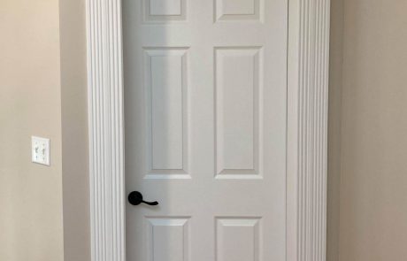 white door with decorative door frame and black metal handle inside a seapearl place home