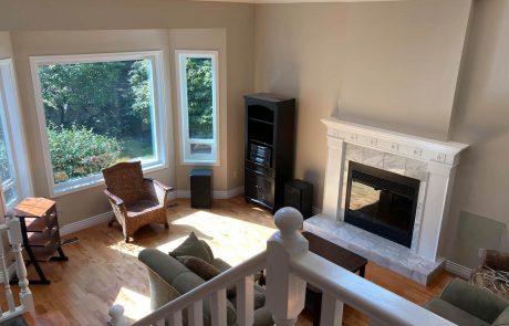 overlooking the living room with a tiled fireplace and large windows facing a garden