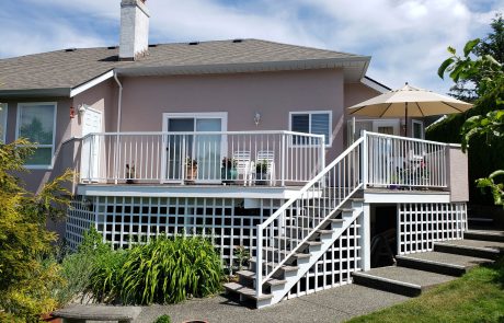 Pink house with a back patio and stairs that lead to a garden